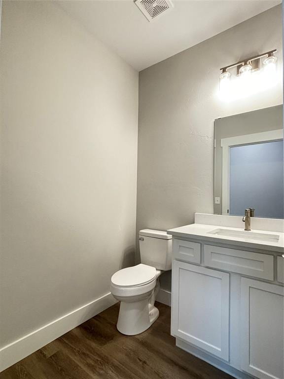 bathroom with toilet, wood finished floors, visible vents, and baseboards