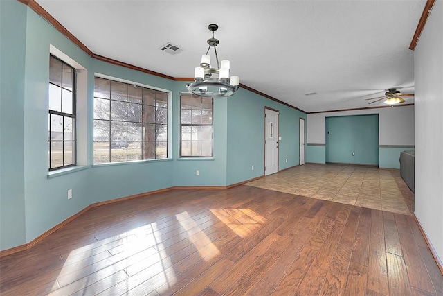 empty room featuring visible vents, crown molding, baseboards, and hardwood / wood-style flooring