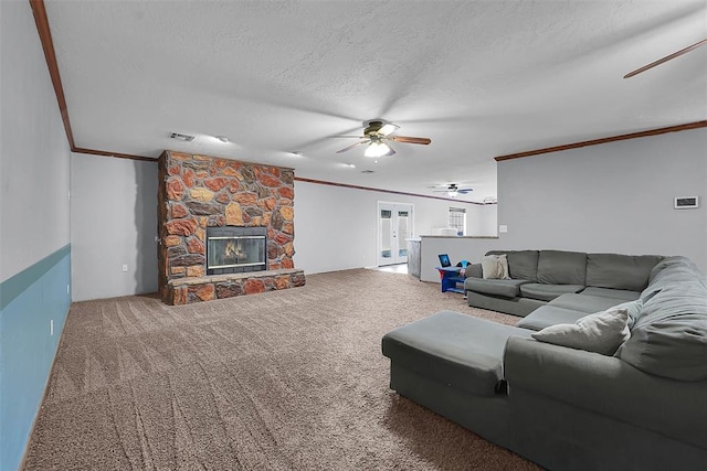 living room featuring carpet flooring, a textured ceiling, a ceiling fan, and ornamental molding