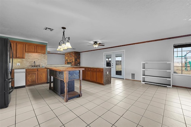 kitchen with light tile patterned floors, visible vents, crown molding, and freestanding refrigerator