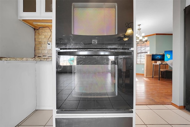 kitchen featuring a wealth of natural light, backsplash, a notable chandelier, and white cabinets