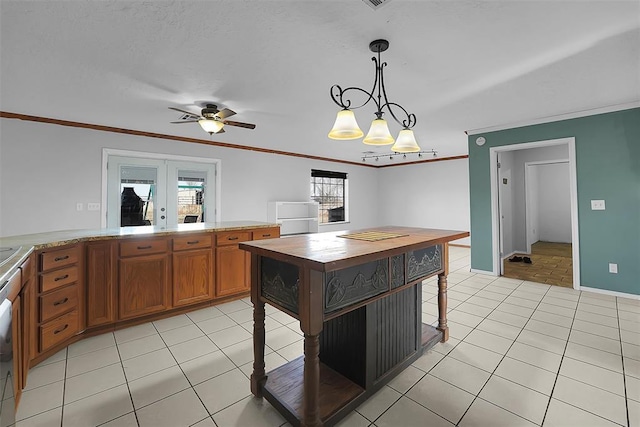 kitchen featuring french doors, light tile patterned flooring, brown cabinetry, and crown molding