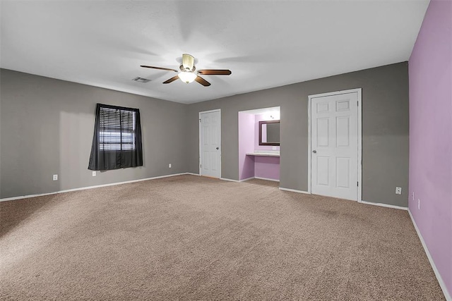 carpeted spare room with visible vents, baseboards, and a ceiling fan