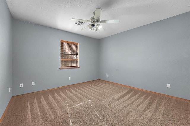 carpeted spare room with visible vents, baseboards, a textured ceiling, and a ceiling fan