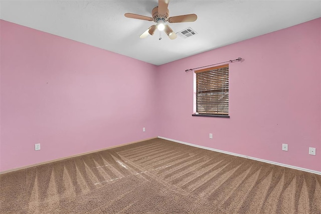 carpeted spare room featuring visible vents, baseboards, and ceiling fan