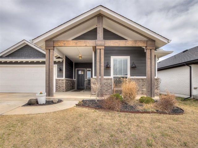 craftsman house with a front lawn, covered porch, concrete driveway, an attached garage, and brick siding