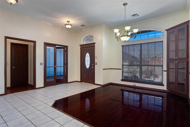 entryway with visible vents, baseboards, an inviting chandelier, and ornamental molding