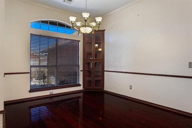 unfurnished room with a wealth of natural light, wood-type flooring, a notable chandelier, and ornamental molding