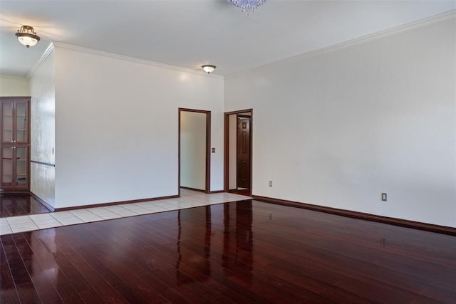 empty room with baseboards, wood finished floors, and crown molding