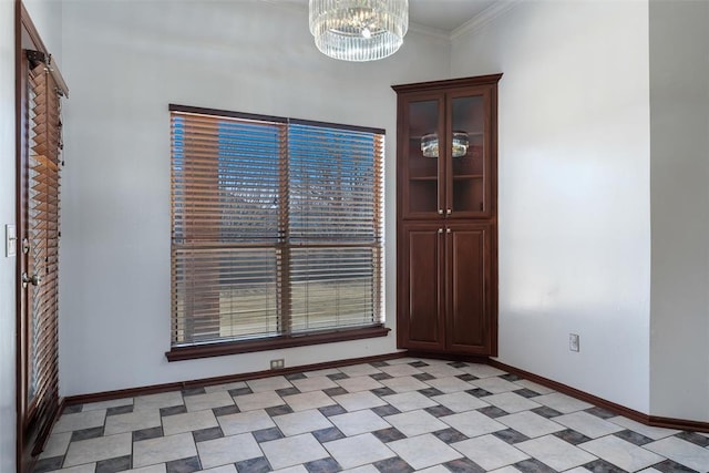 interior space with light floors, baseboards, a chandelier, and ornamental molding