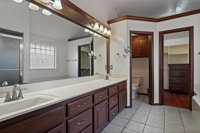 bathroom with tile patterned floors, toilet, a shower with shower door, and a sink