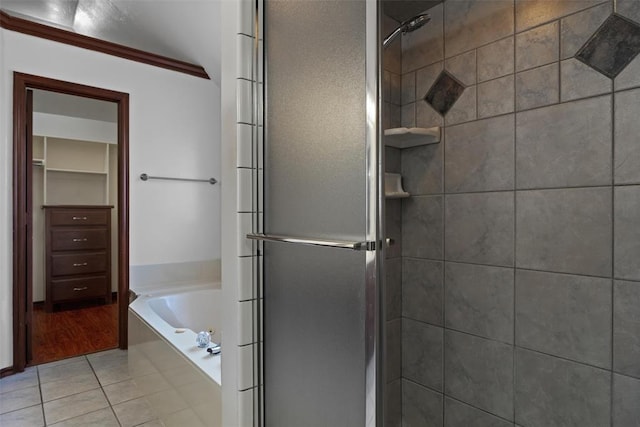 bathroom featuring tile patterned floors, a walk in closet, a garden tub, and a shower stall