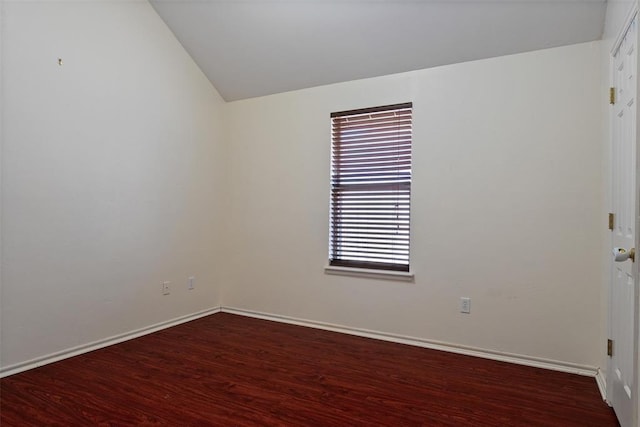 empty room featuring vaulted ceiling, wood finished floors, and baseboards