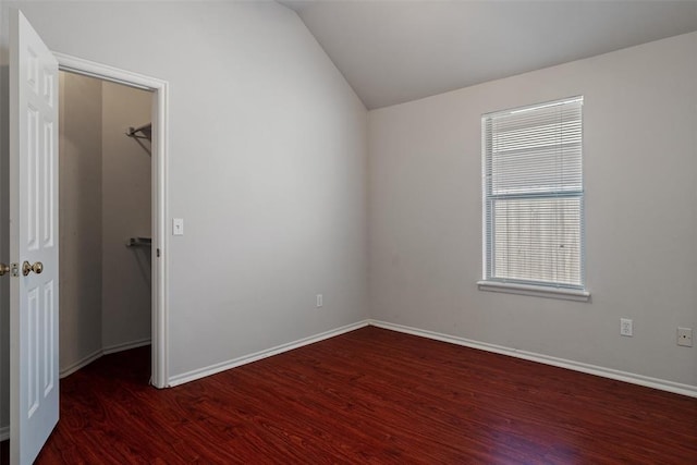 spare room featuring baseboards, lofted ceiling, and wood finished floors