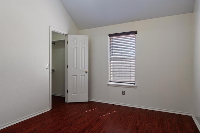 unfurnished room with wood finished floors, baseboards, and vaulted ceiling