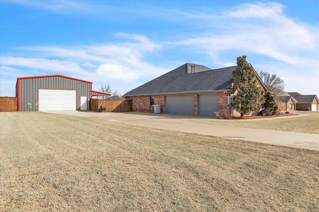 view of home's exterior with brick siding, central AC unit, roof with shingles, and fence