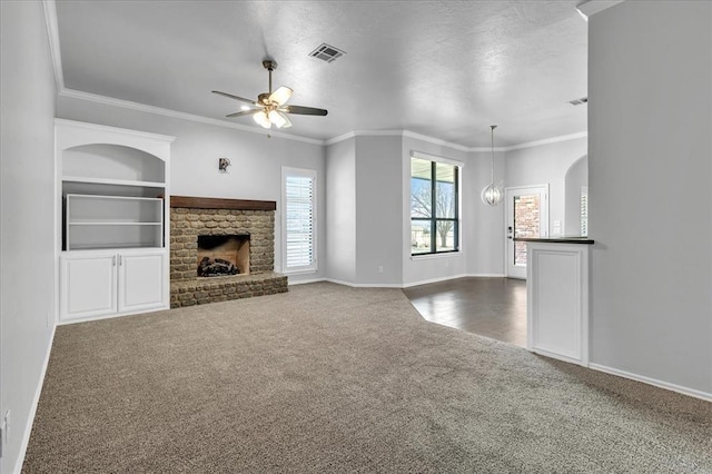 unfurnished living room with visible vents, built in shelves, carpet, ceiling fan with notable chandelier, and a fireplace