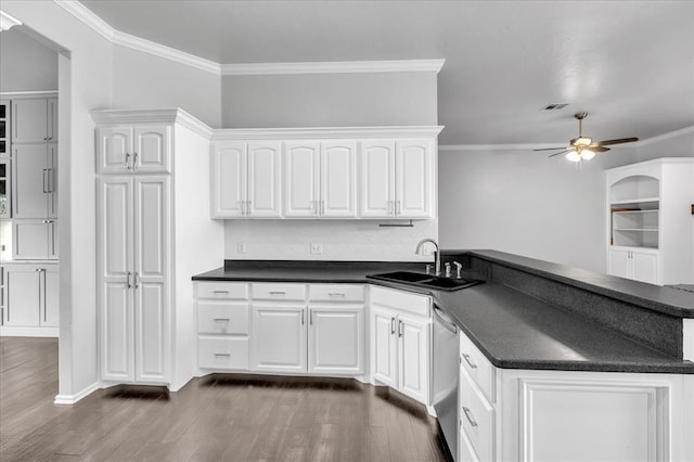 kitchen featuring dark countertops, dishwasher, a peninsula, white cabinets, and a sink