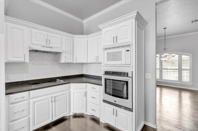 kitchen featuring under cabinet range hood, dark countertops, oven, and white microwave