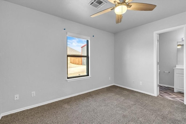 carpeted spare room featuring baseboards, visible vents, and ceiling fan