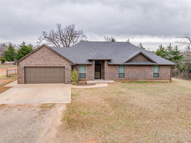 view of front of home featuring a garage, a front lawn, driveway, and a shingled roof