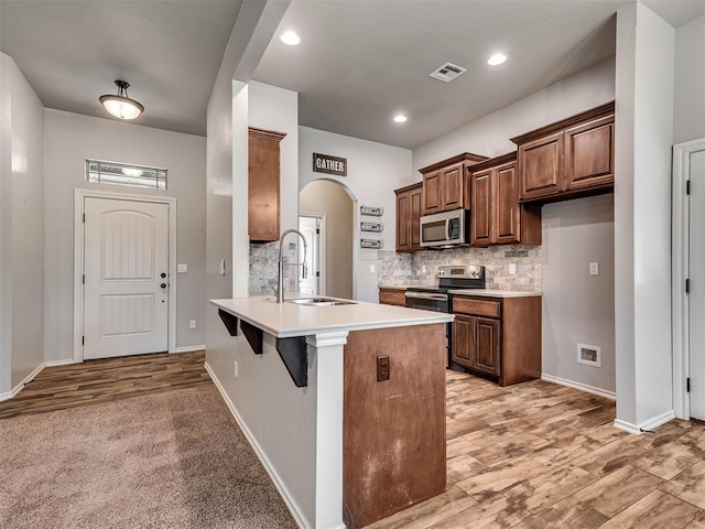 kitchen featuring visible vents, backsplash, appliances with stainless steel finishes, arched walkways, and a sink