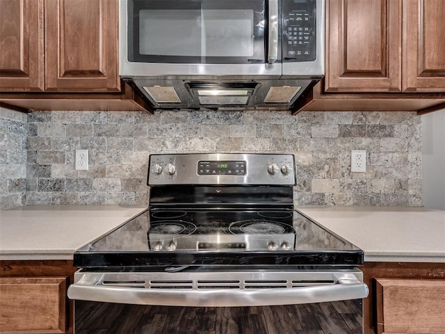 kitchen featuring brown cabinetry, decorative backsplash, appliances with stainless steel finishes, and light countertops