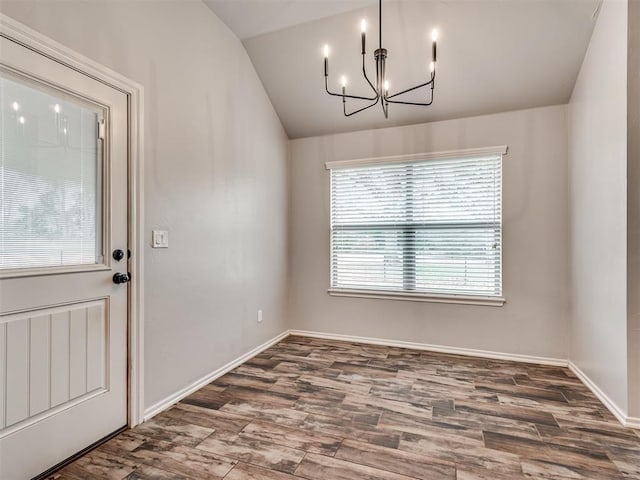 unfurnished dining area with baseboards, lofted ceiling, an inviting chandelier, and wood finished floors