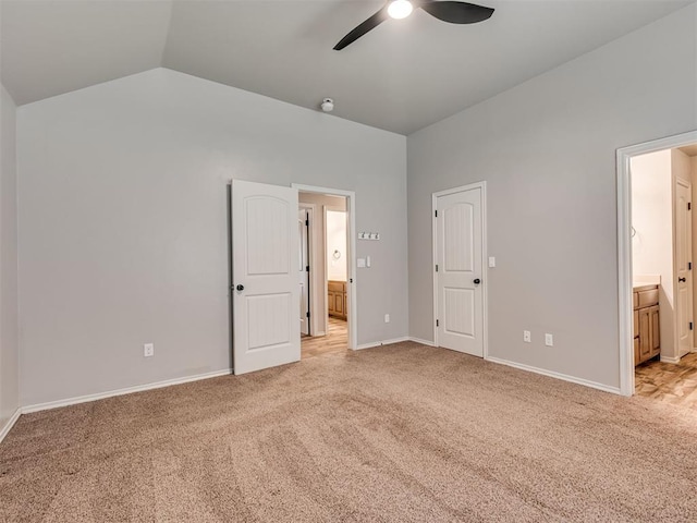 unfurnished bedroom with baseboards, vaulted ceiling, light carpet, ensuite bath, and a ceiling fan