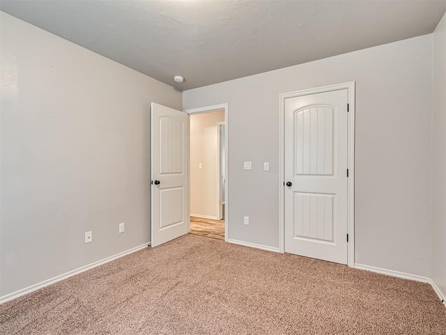 unfurnished bedroom featuring baseboards and light colored carpet