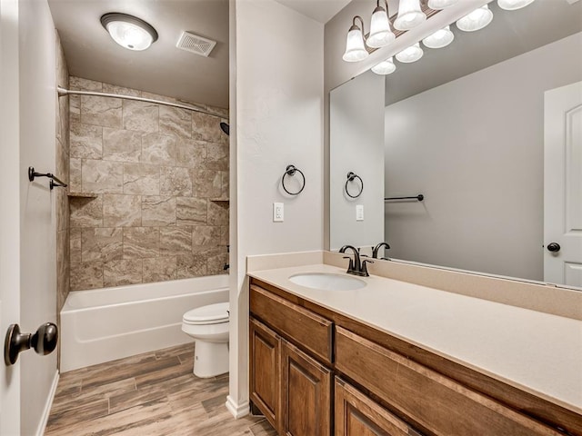 bathroom with visible vents, toilet, wood finished floors, bathing tub / shower combination, and vanity