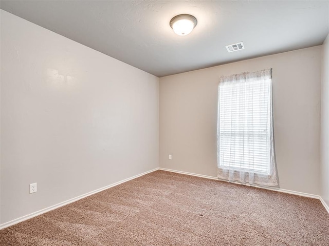 spare room featuring visible vents, baseboards, and carpet flooring