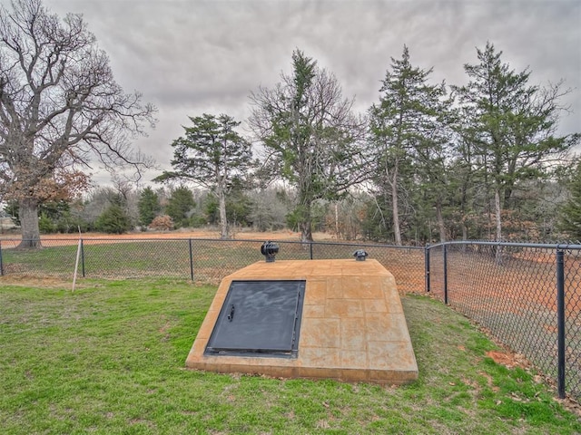 view of storm shelter featuring a fenced backyard and a yard