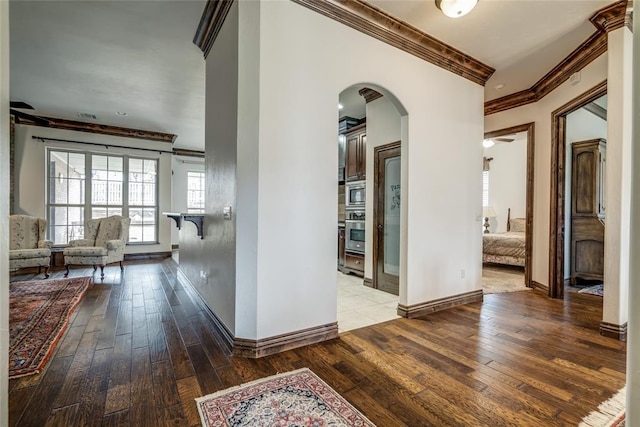 hallway with baseboards, arched walkways, hardwood / wood-style floors, and crown molding