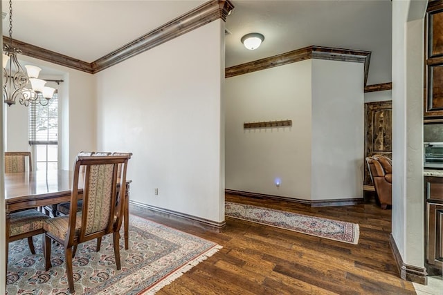 dining area with an inviting chandelier, crown molding, wood finished floors, and baseboards