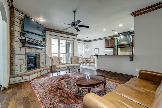 living area featuring ornamental molding, recessed lighting, a fireplace, ceiling fan, and dark wood-style flooring