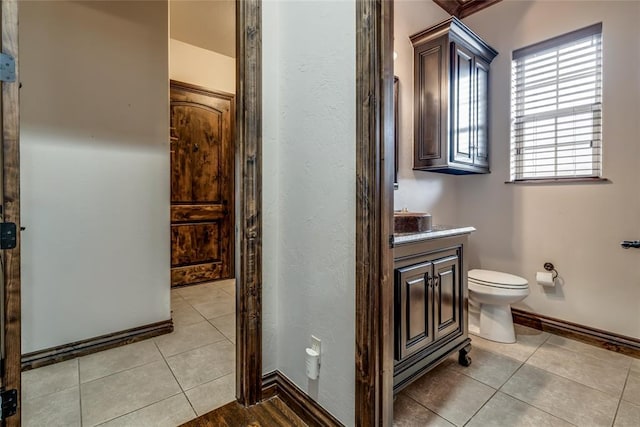 bathroom with tile patterned flooring, toilet, vanity, and baseboards