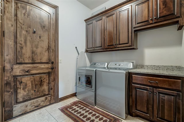 laundry area featuring light tile patterned floors, baseboards, cabinet space, and washing machine and dryer