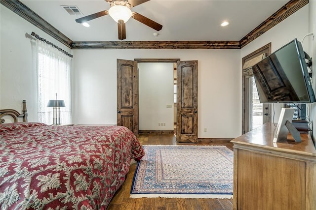 bedroom with visible vents, crown molding, ceiling fan, and wood finished floors