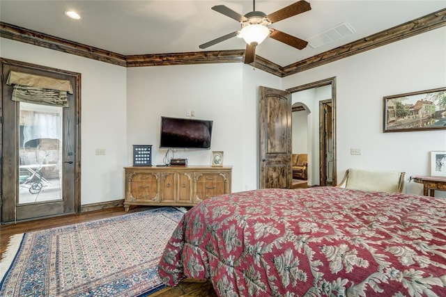 bedroom featuring wood finished floors, arched walkways, visible vents, and ornamental molding