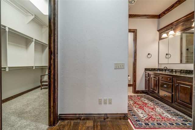 bathroom featuring vanity, crown molding, baseboards, and a textured wall