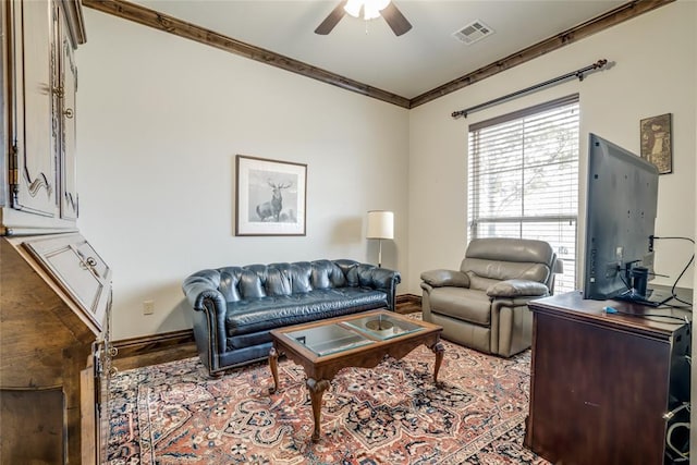 living room with ceiling fan, baseboards, visible vents, and ornamental molding