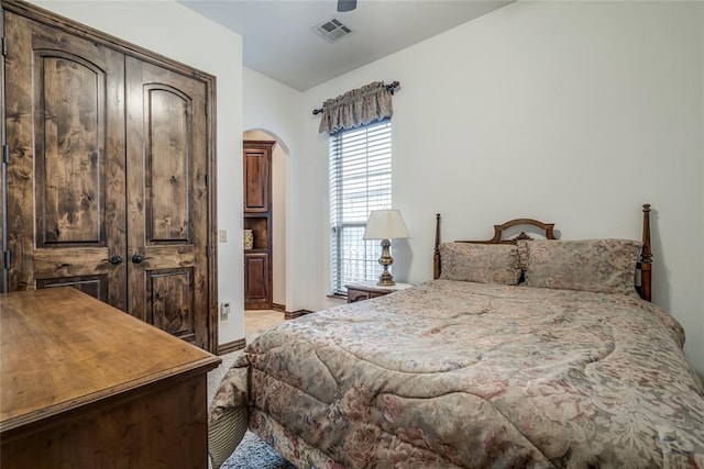 bedroom with a ceiling fan, visible vents, arched walkways, light carpet, and connected bathroom