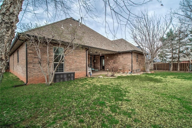 back of property featuring brick siding, a lawn, a patio, and fence