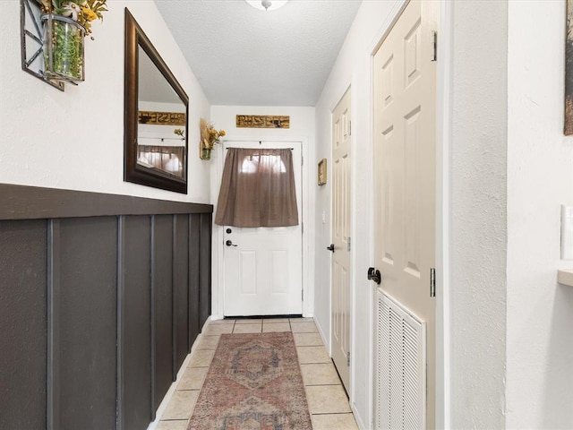 doorway to outside featuring light tile patterned floors, visible vents, and a textured ceiling