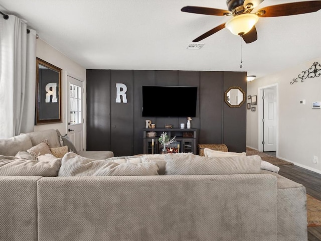 living area featuring visible vents, baseboards, ceiling fan, and wood finished floors