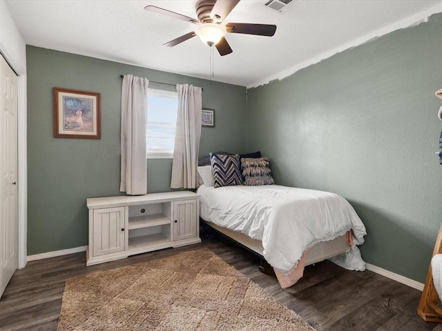 bedroom featuring a closet, baseboards, dark wood-type flooring, and ceiling fan