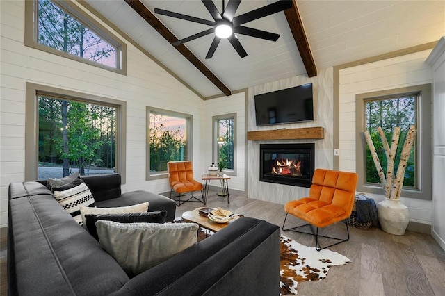 living area featuring beam ceiling, high vaulted ceiling, a ceiling fan, wood finished floors, and a fireplace