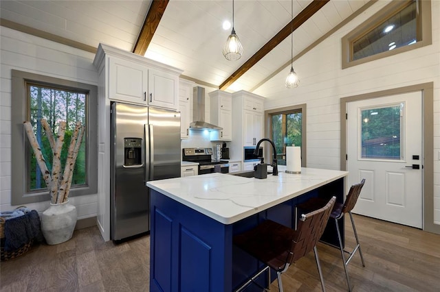 kitchen featuring vaulted ceiling with beams, wall chimney range hood, dark wood-style floors, white cabinets, and stainless steel appliances