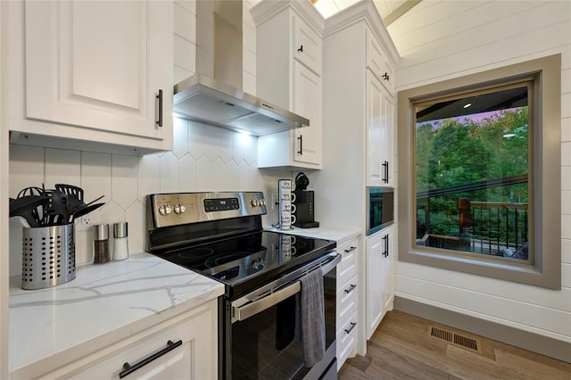 kitchen with electric range, visible vents, white cabinetry, wall chimney range hood, and decorative backsplash